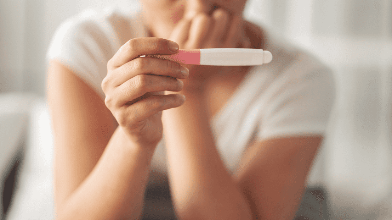 A woman looking at a pregnancy test.