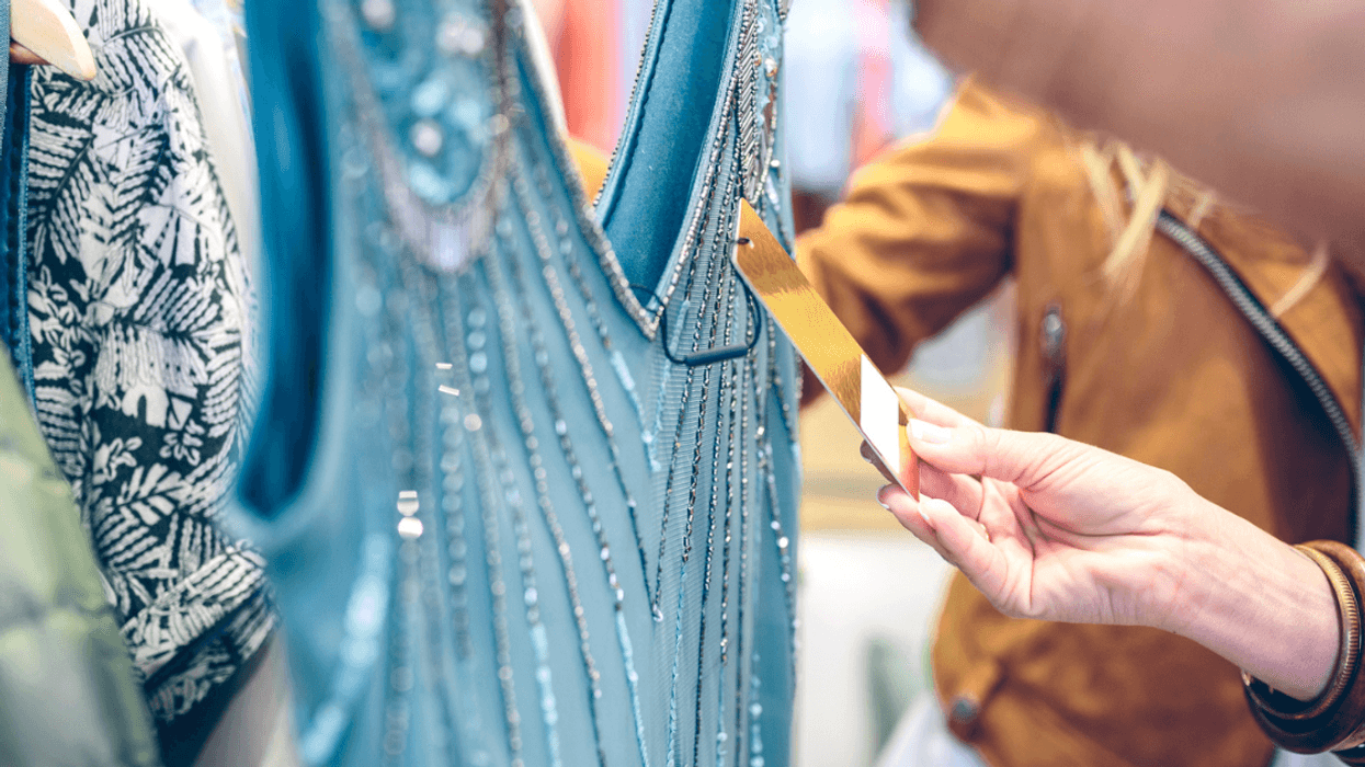 A woman looking at a price tag of a dress on a rack.