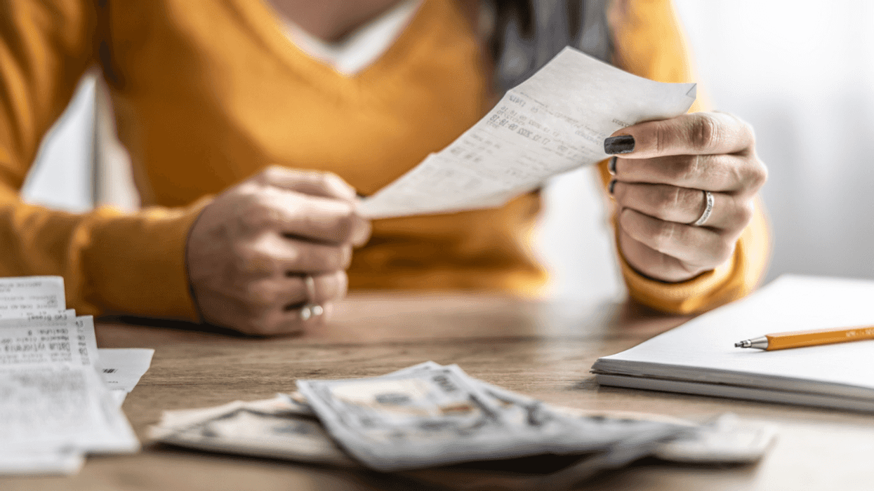 A woman looking at receipts with money and a notebook on the table.