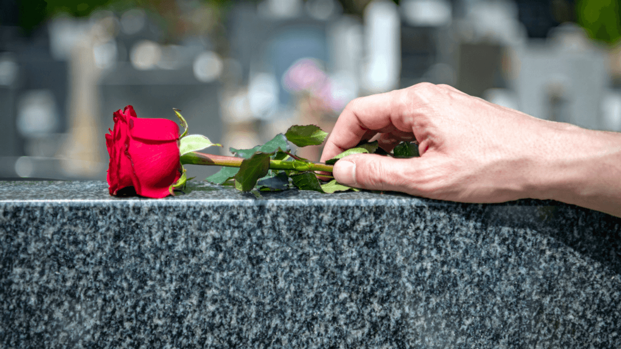 A woman placing a flower on a tombstone