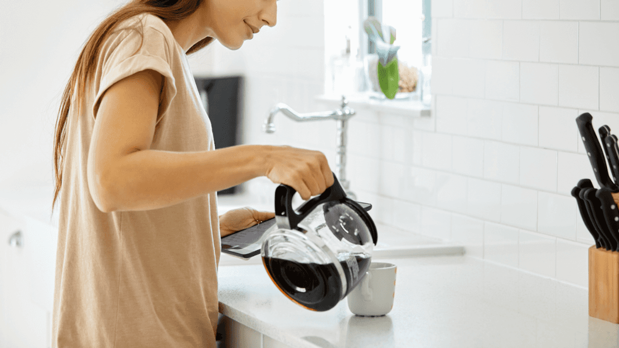 A woman pouring coffee into a mug at the kitchen counter.