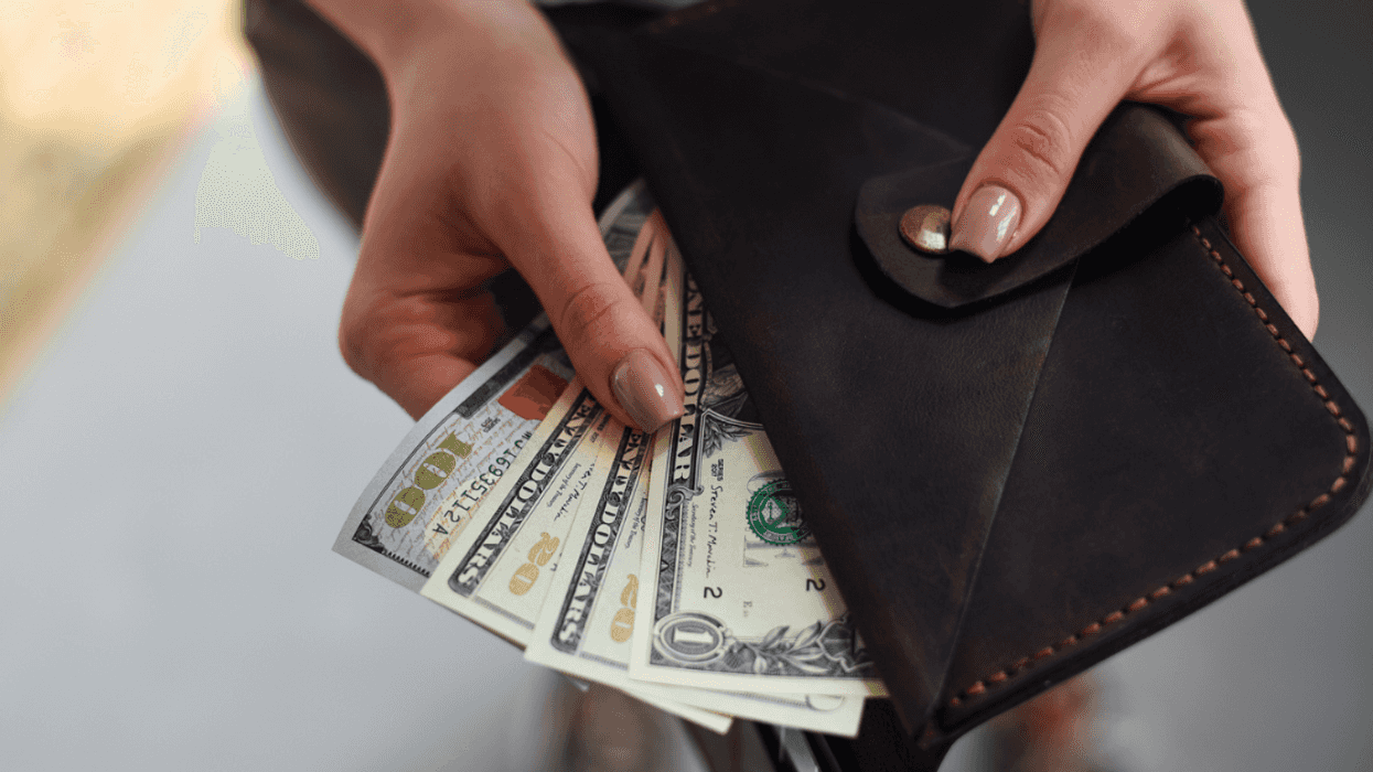 A woman pulling cash bills out of a wallet.