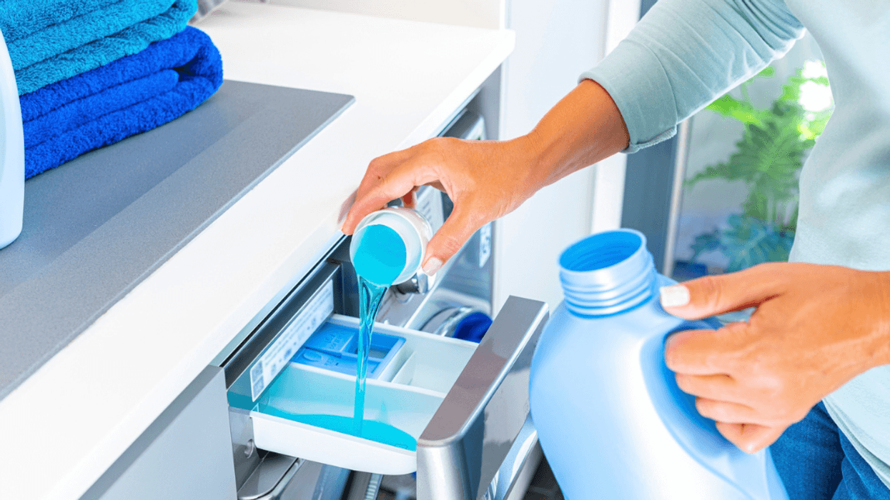 A woman putting laundry detergent in a washing machine.