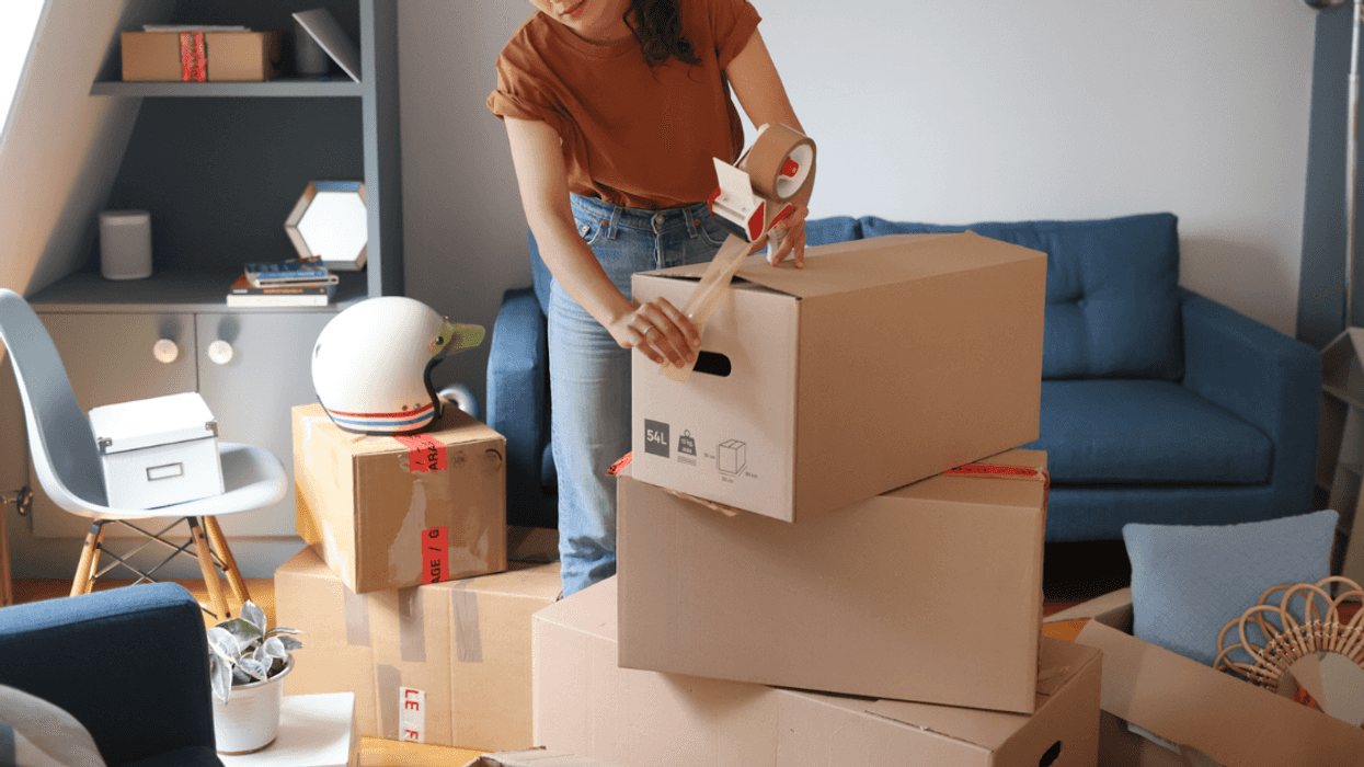 A woman putting tape on a moving box.