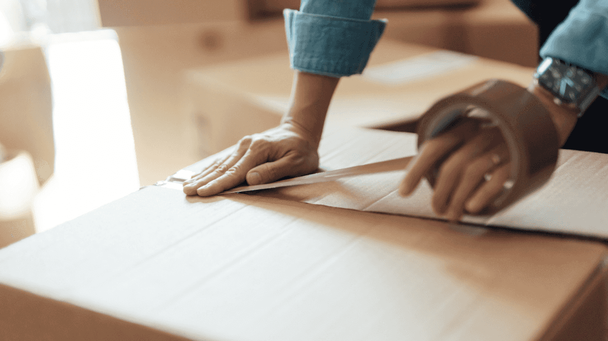 A woman putting tape on a moving box.
