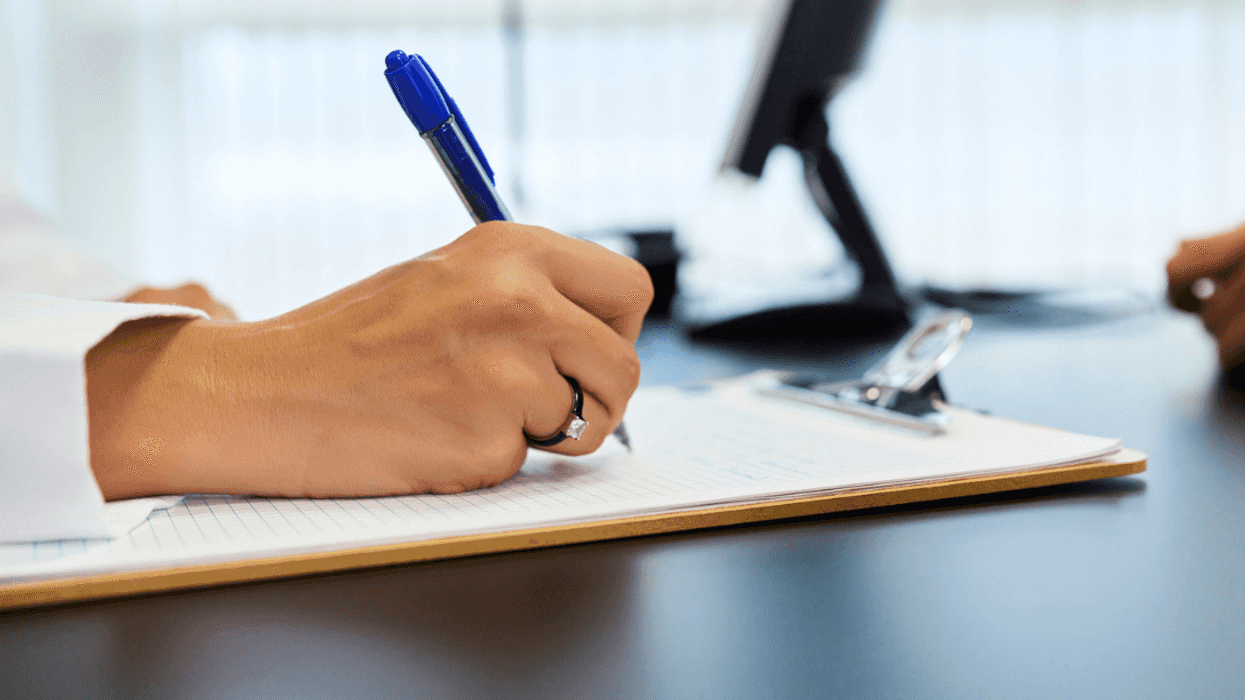 A woman's hand writing on a clipboard.