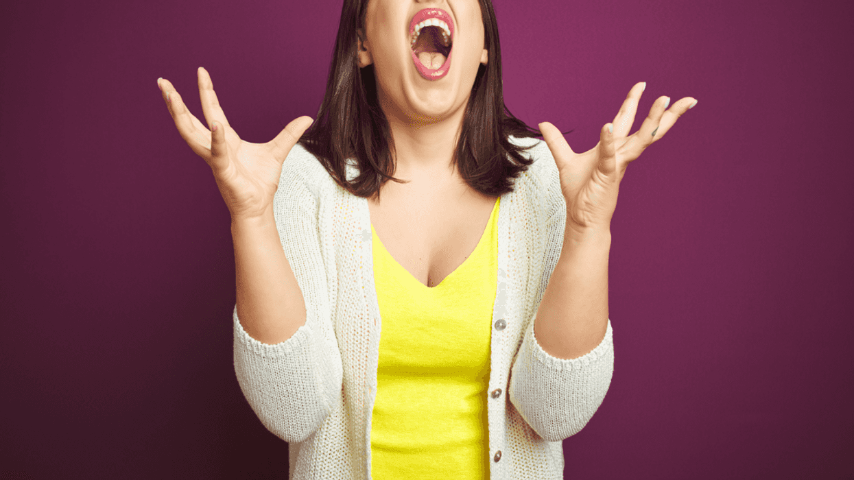 A woman screaming throwing her hands in the air.