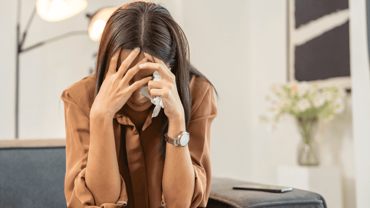 A woman sitting down with her head in her hands.