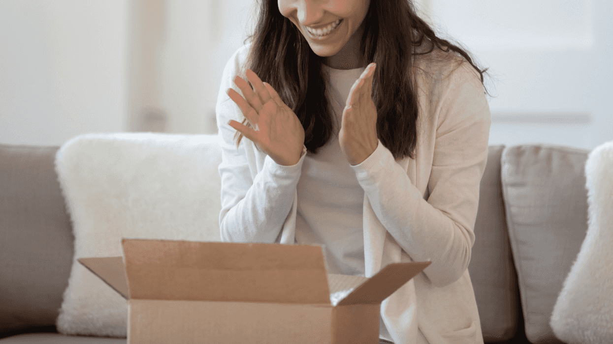 A woman sitting in front of an open cardboard box.