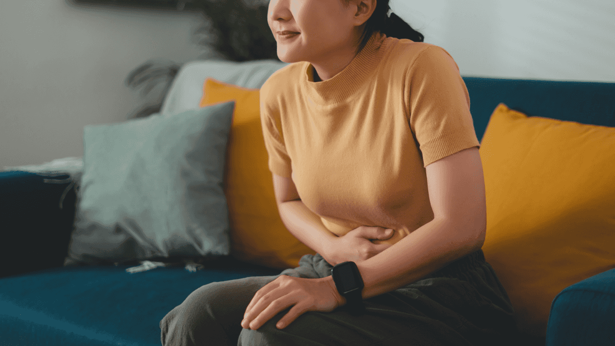 A woman sitting on a sofa, holding her stomach.