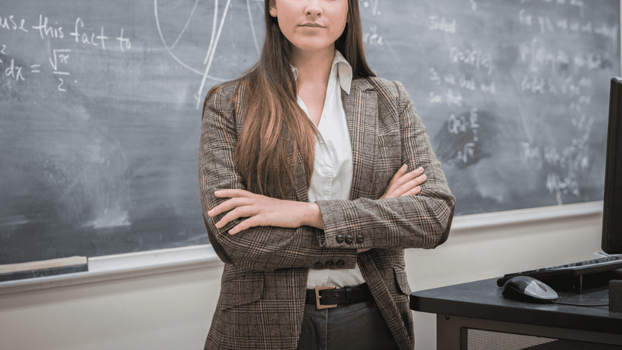 A woman standing in front of a chalk board with her arms crossed.