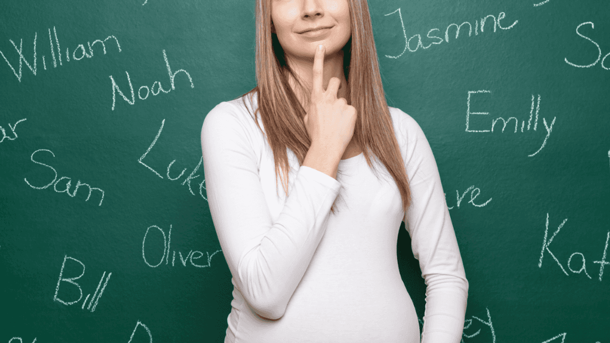 A woman standing in front of a chalkboard with names written on it.