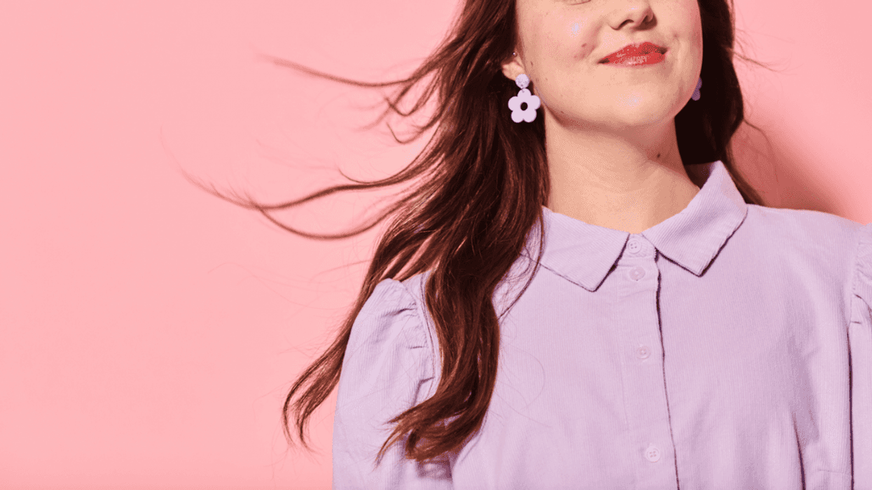 A woman standing in front of a pink wall.