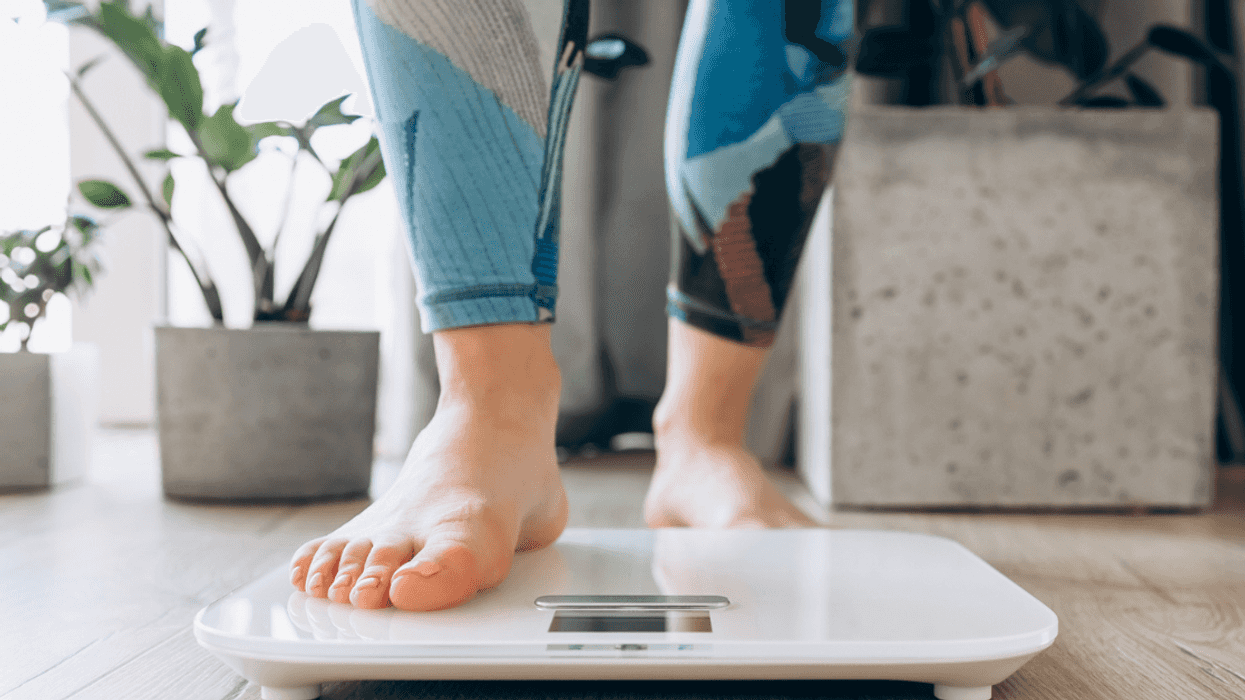 A woman stepping on a scale.