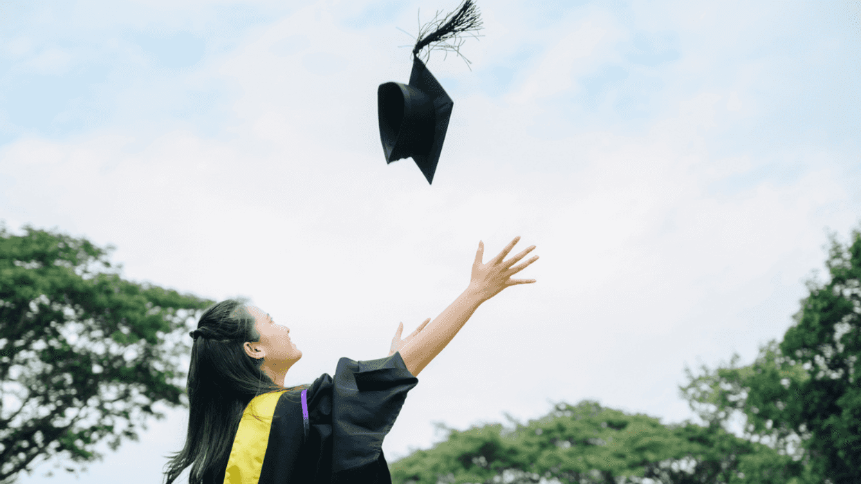 A woman throwing a graduation cap in the air.