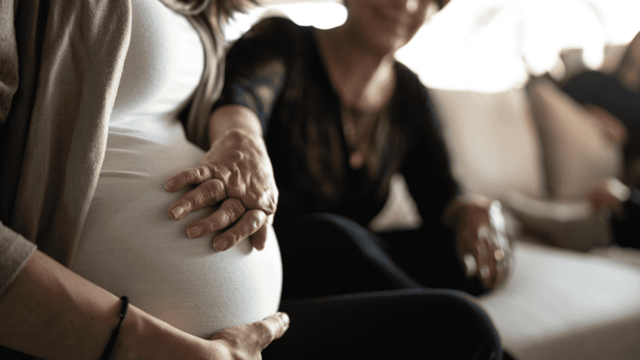 A woman touching a pregnant woman's belly.