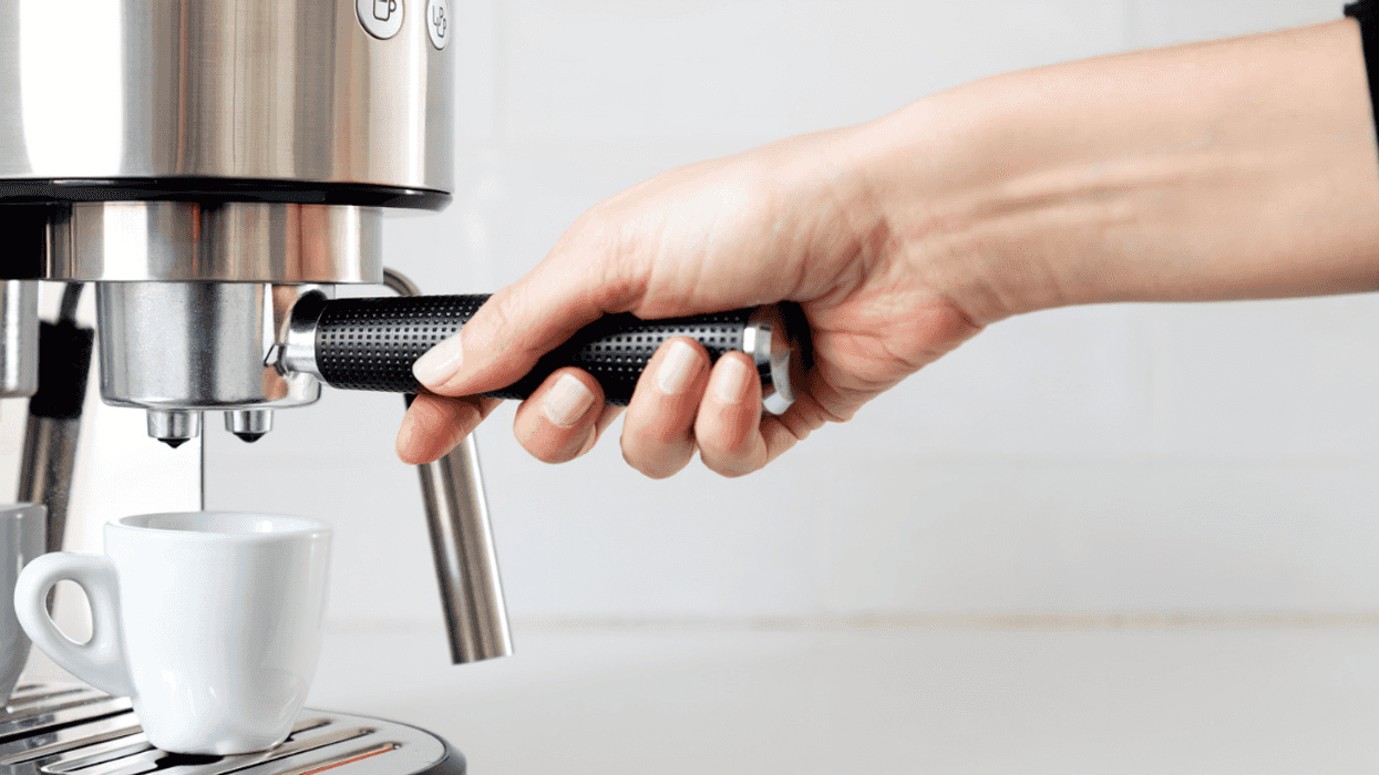 A woman using an espresso machine.