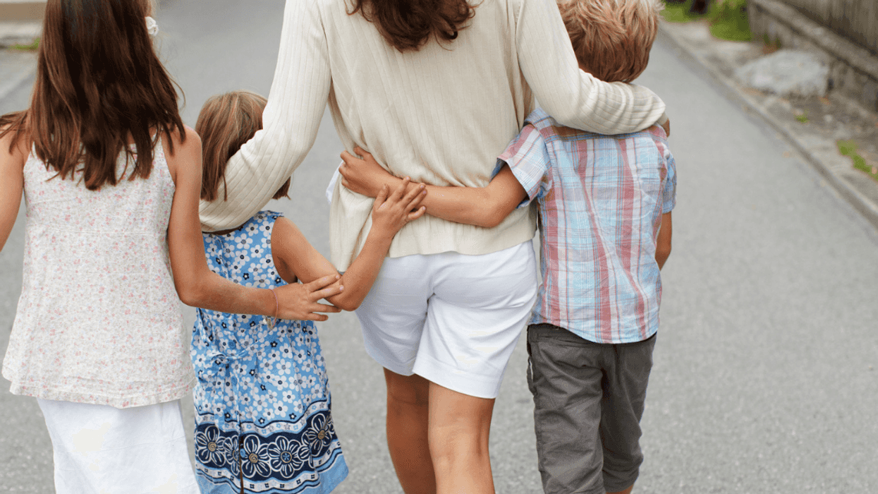 A woman walking with three children.