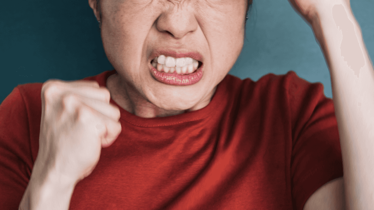 A woman with a clenched jaw holding her fists in the air.