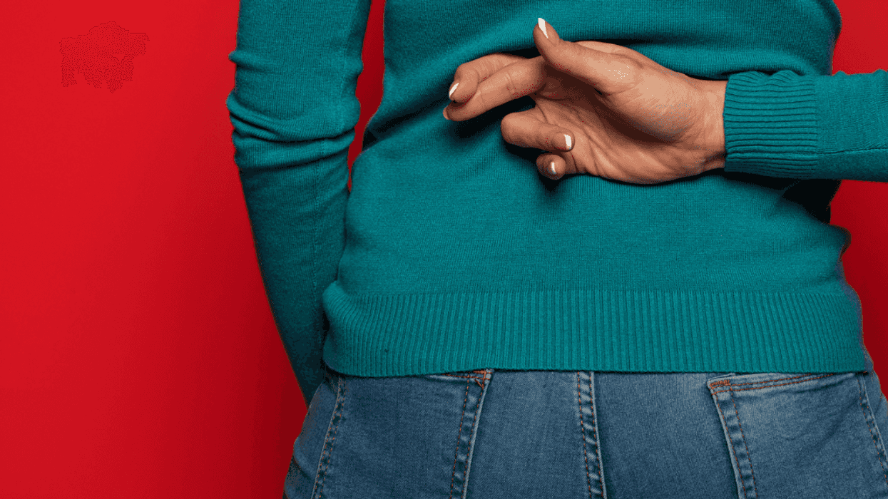 A woman with her fingers crossed behind her back.