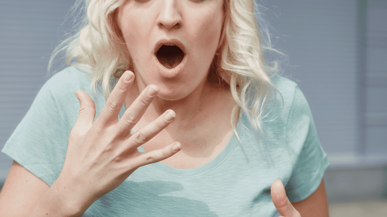 A woman with her mouth open holding her hand close to her mouth.