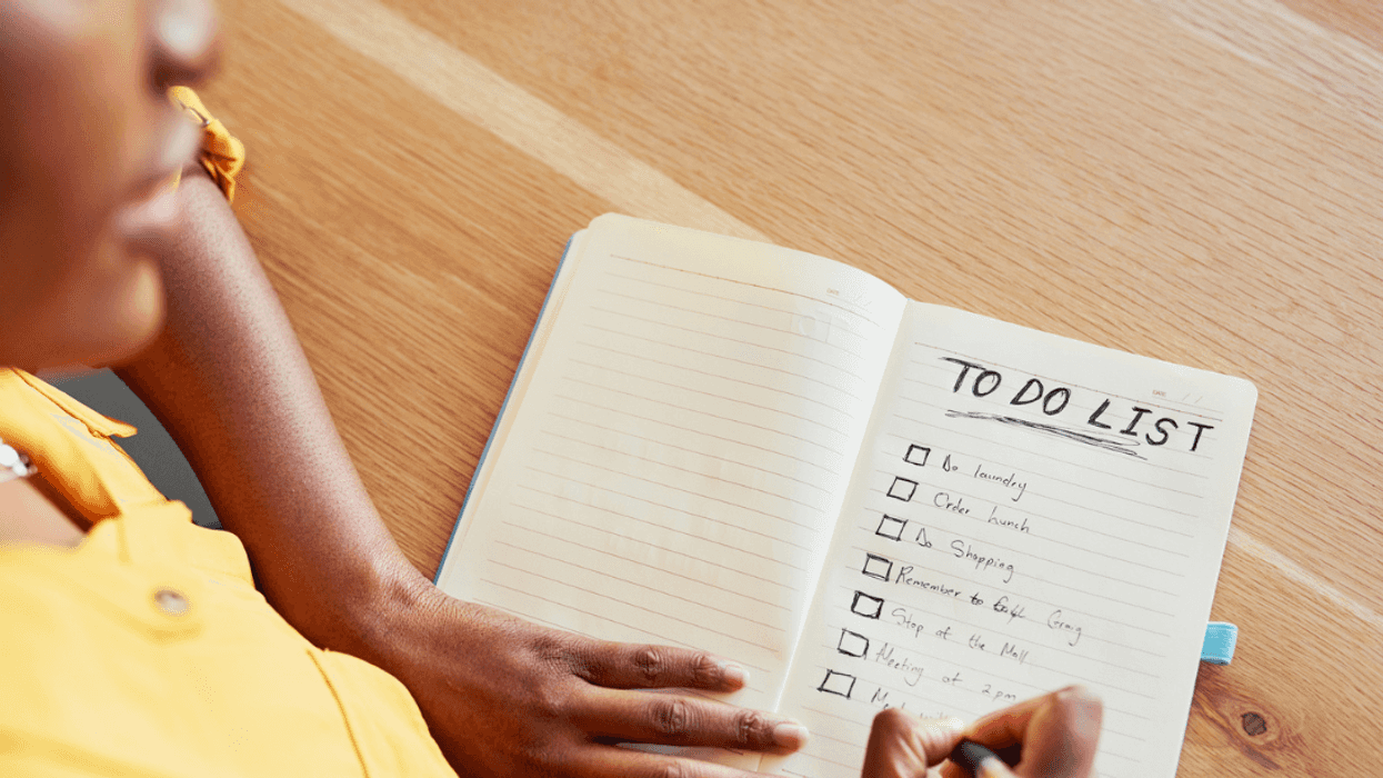 A woman writing a "to do" list in a notebook.