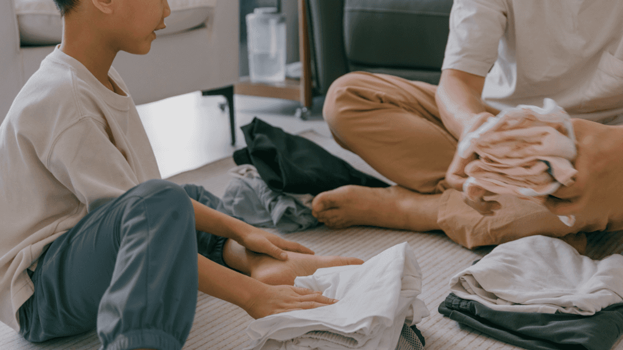 A young boy and an older man folding laundry.