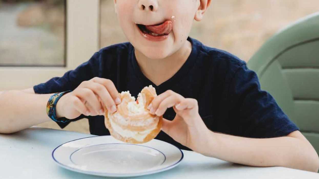 A young boy licks his lips after eating