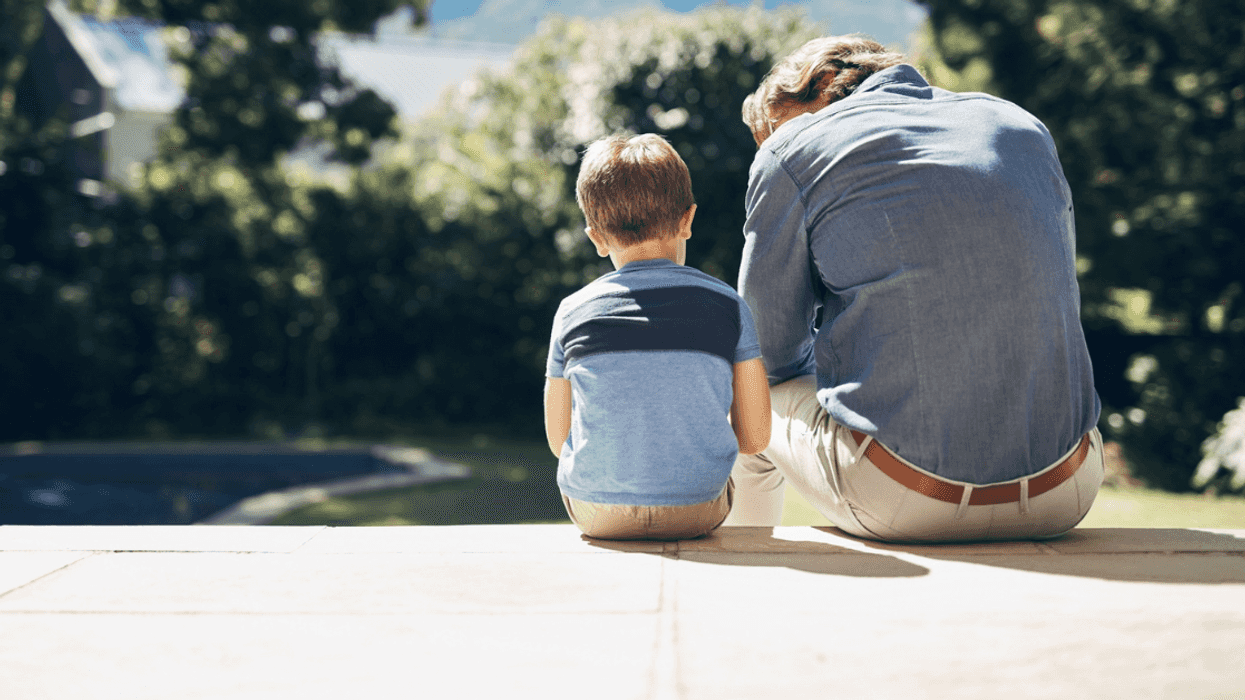 A young boy sitting next to a man looking down to him.