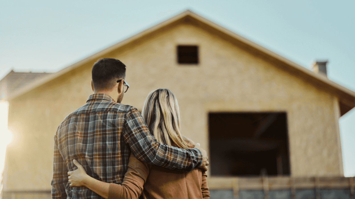 A young couple looking on the foundation of a house.