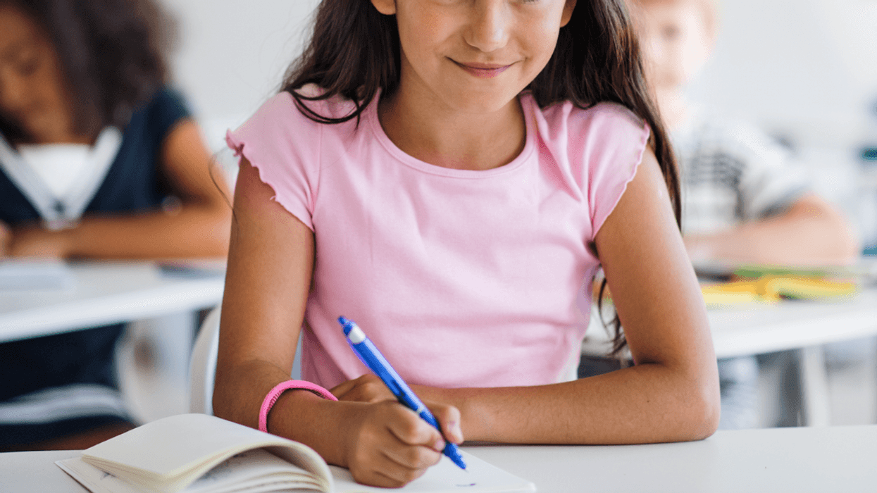 A young girl at her desk in school.