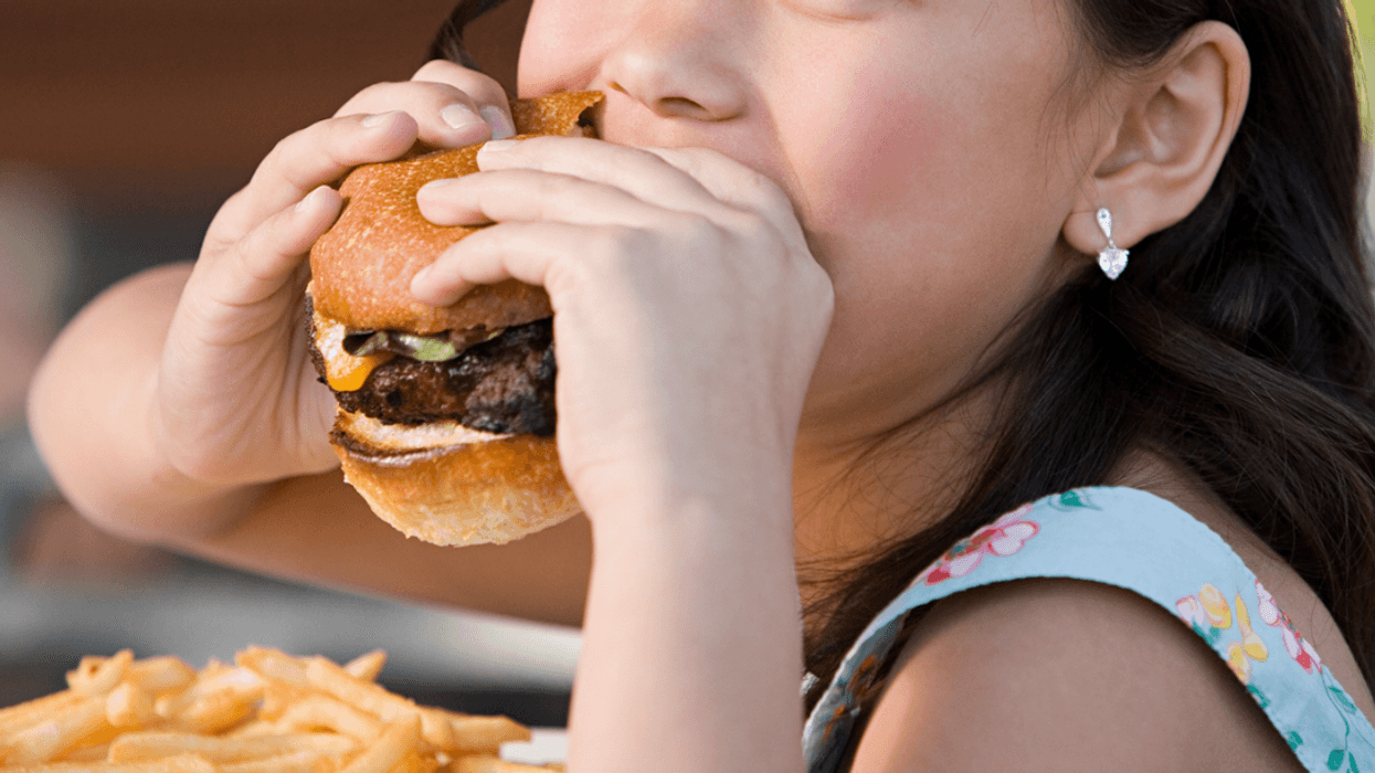 A young girl eating a hamburger.