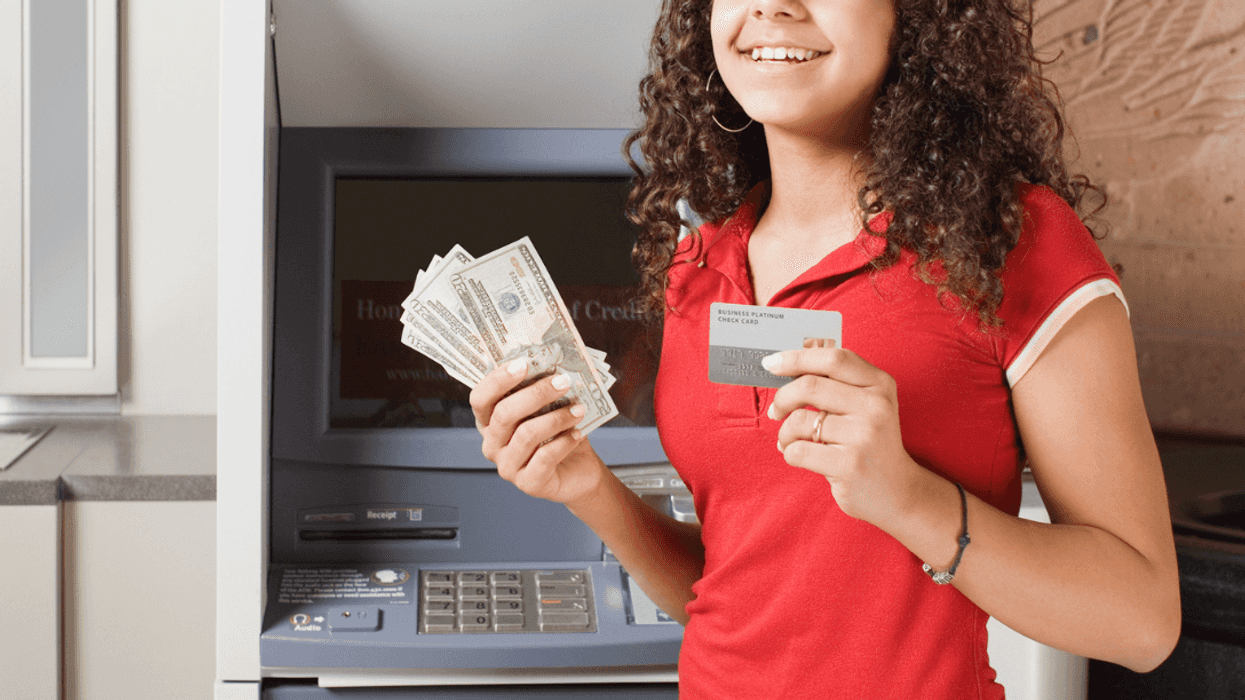 A young girl holding cash in one hand and a credit card in another.