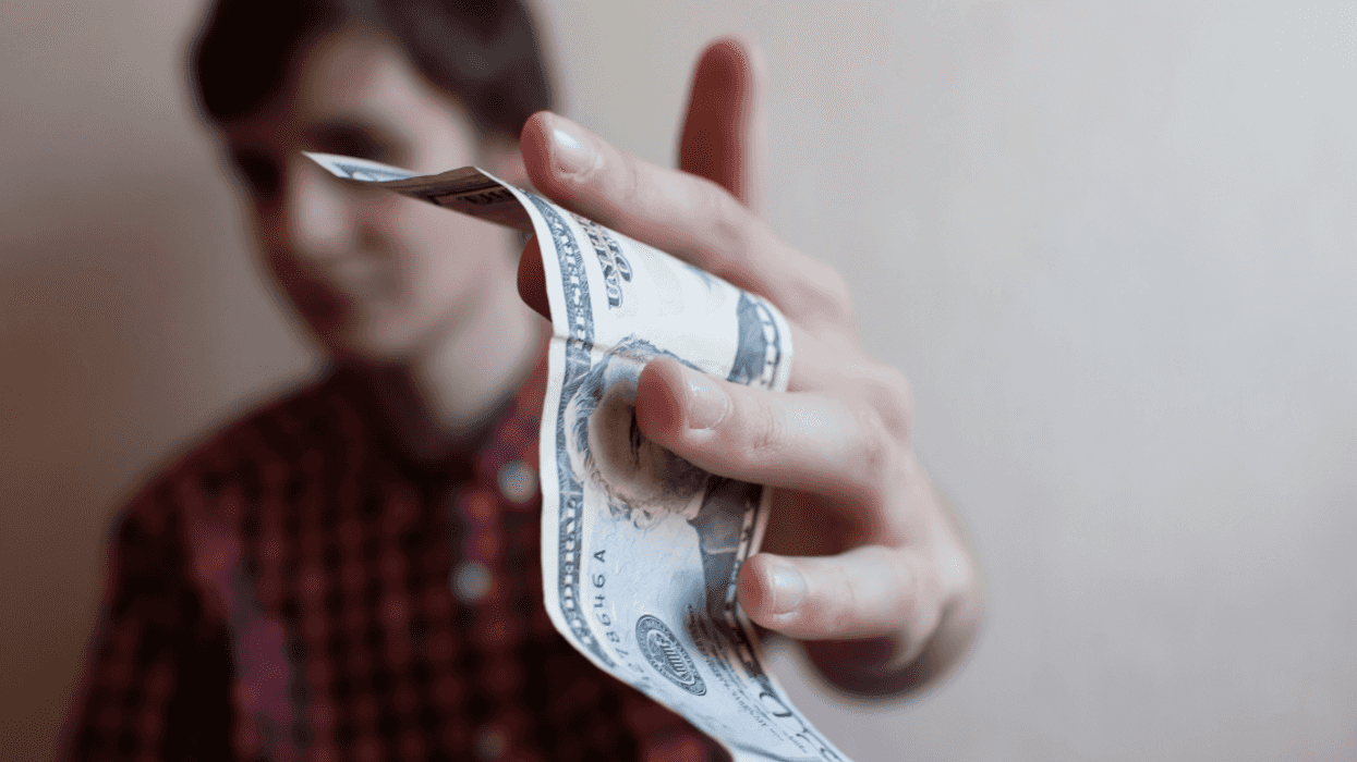 A young man holds out money in his hand.