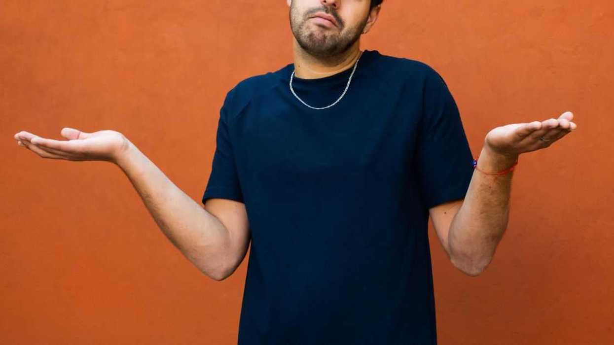 A young man shrugging his shoulders with hands spread out.