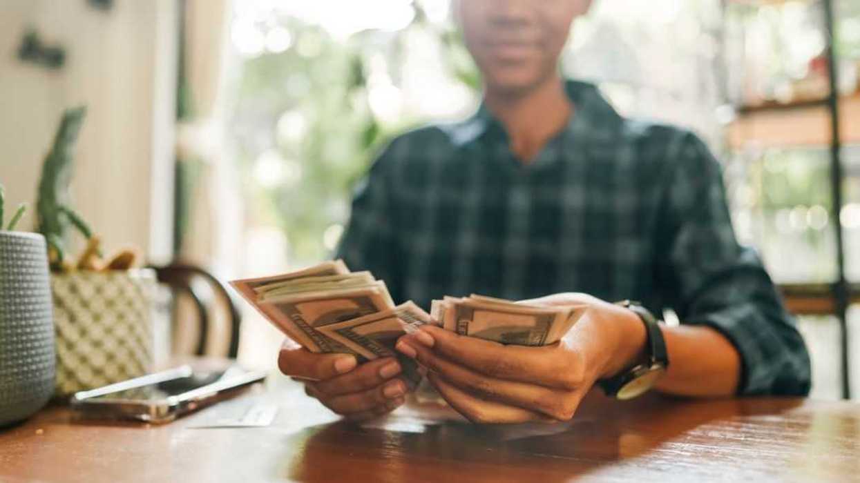 A young woman counts hundred dollar bills.