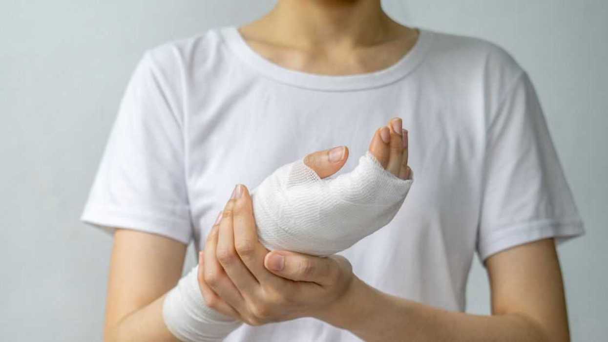 A young woman holds up her bandaged hand.