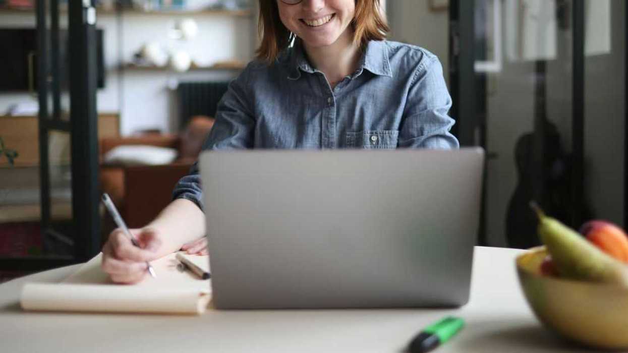 A young woman teleworking at the kitchen table.