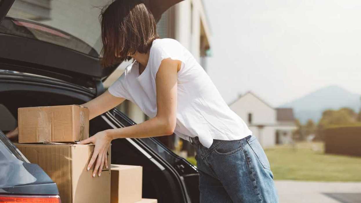 A young woman unloads boxes from her car.