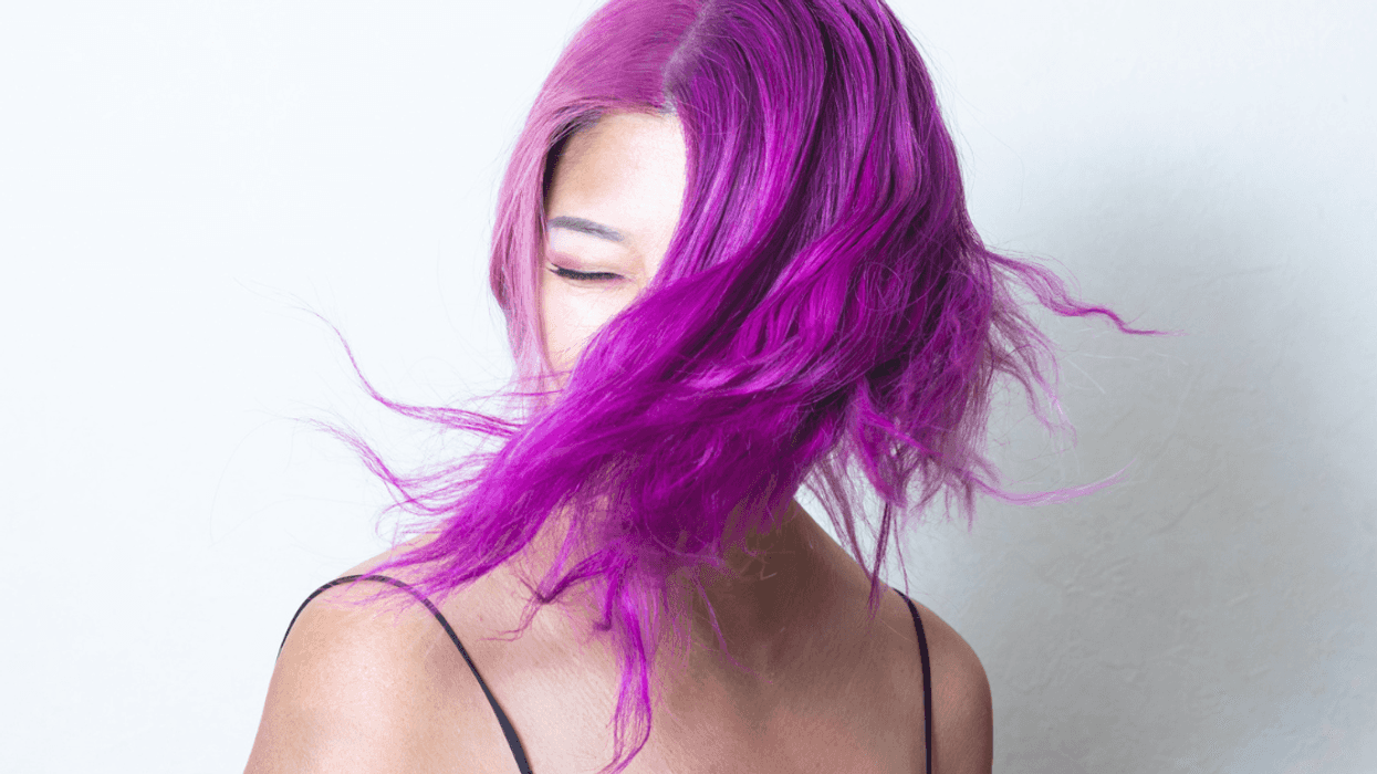 A young woman with purple hair covering her face.