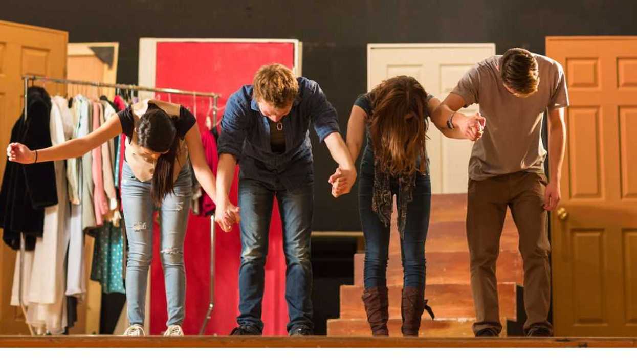 Actors holding hands on stage and bowing.