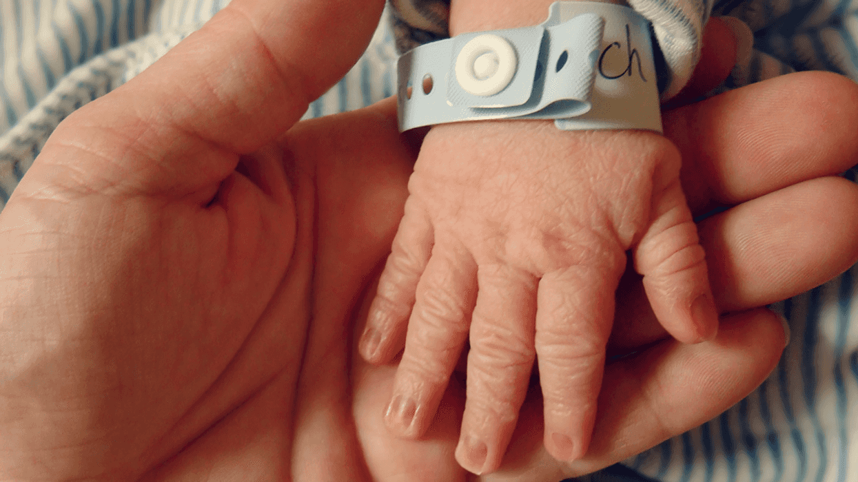adult holding infants hand with hospital bracelet on wrist