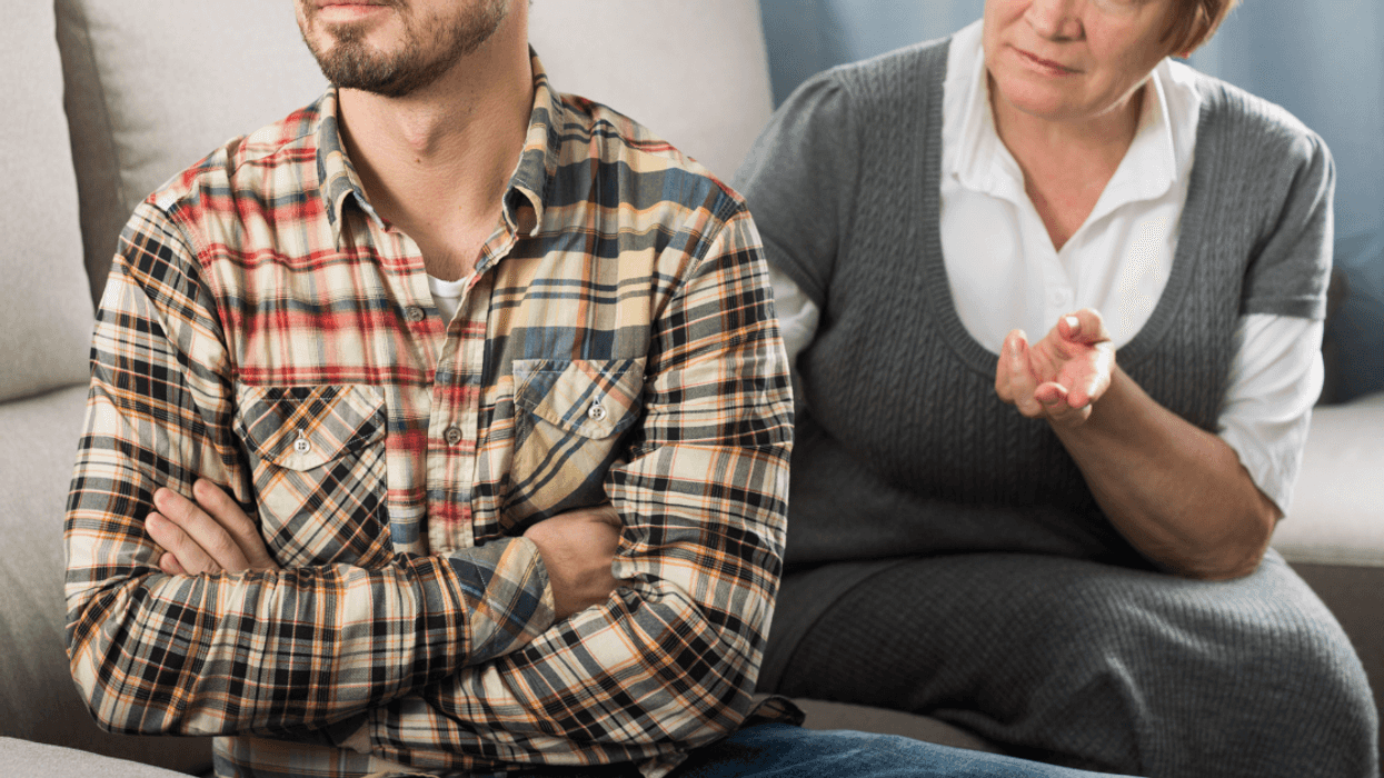 adult son argues with his mother while seated on couch