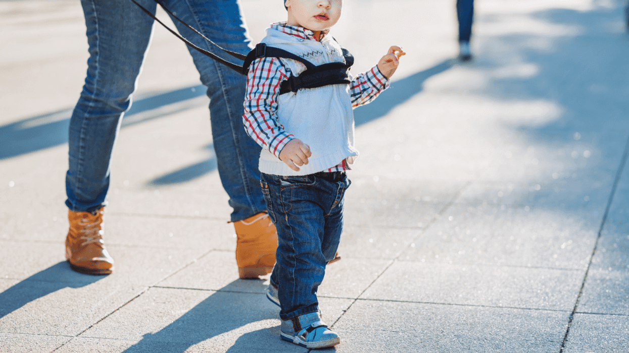 Adult walking with child, using a retractable leash