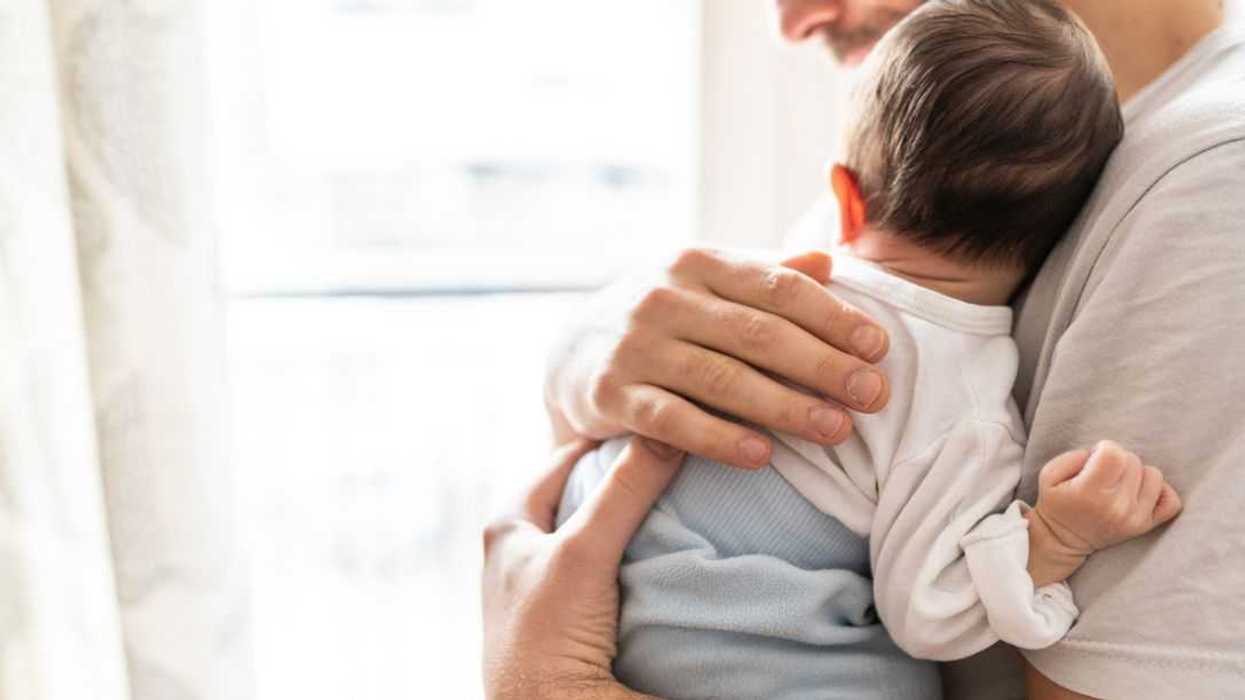 Affectionate love between father and newborn baby, father holding his son in arms in apartment.