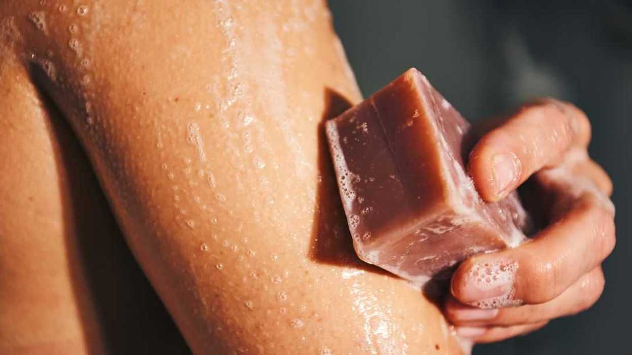 An arm being cleaned with a sudsy handmade soap bar, symbolizing hygiene and skin care.