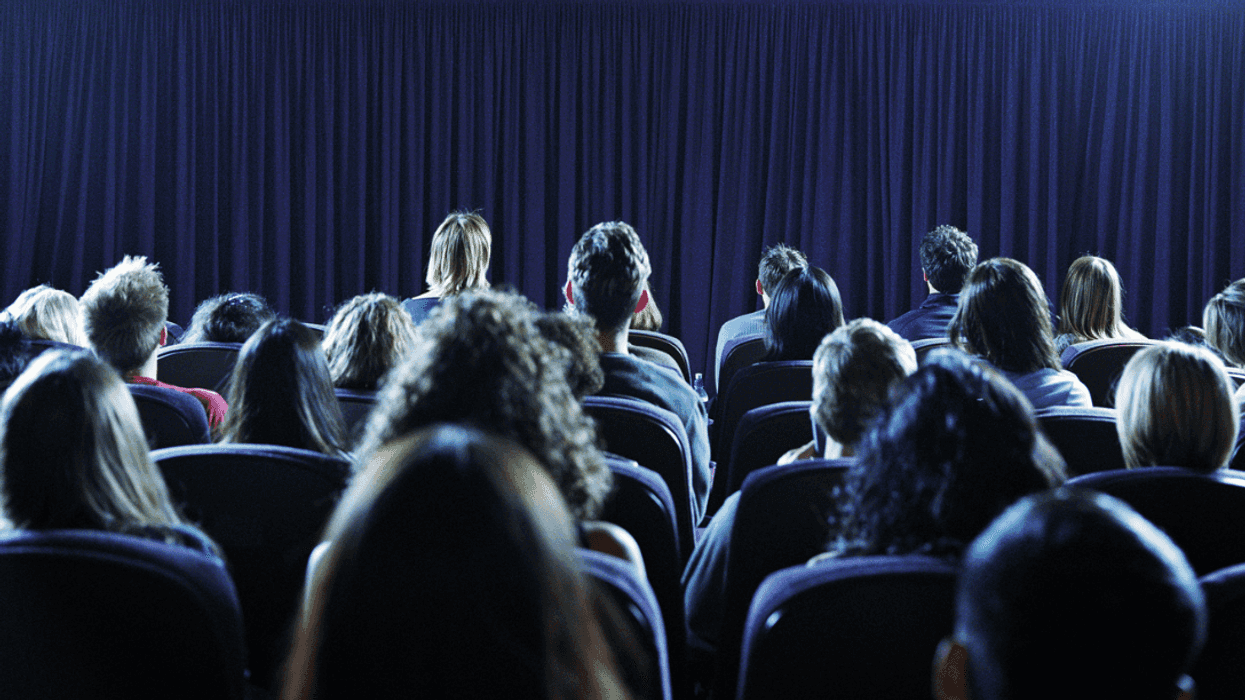 An audience sitting in seats in a dark theater.