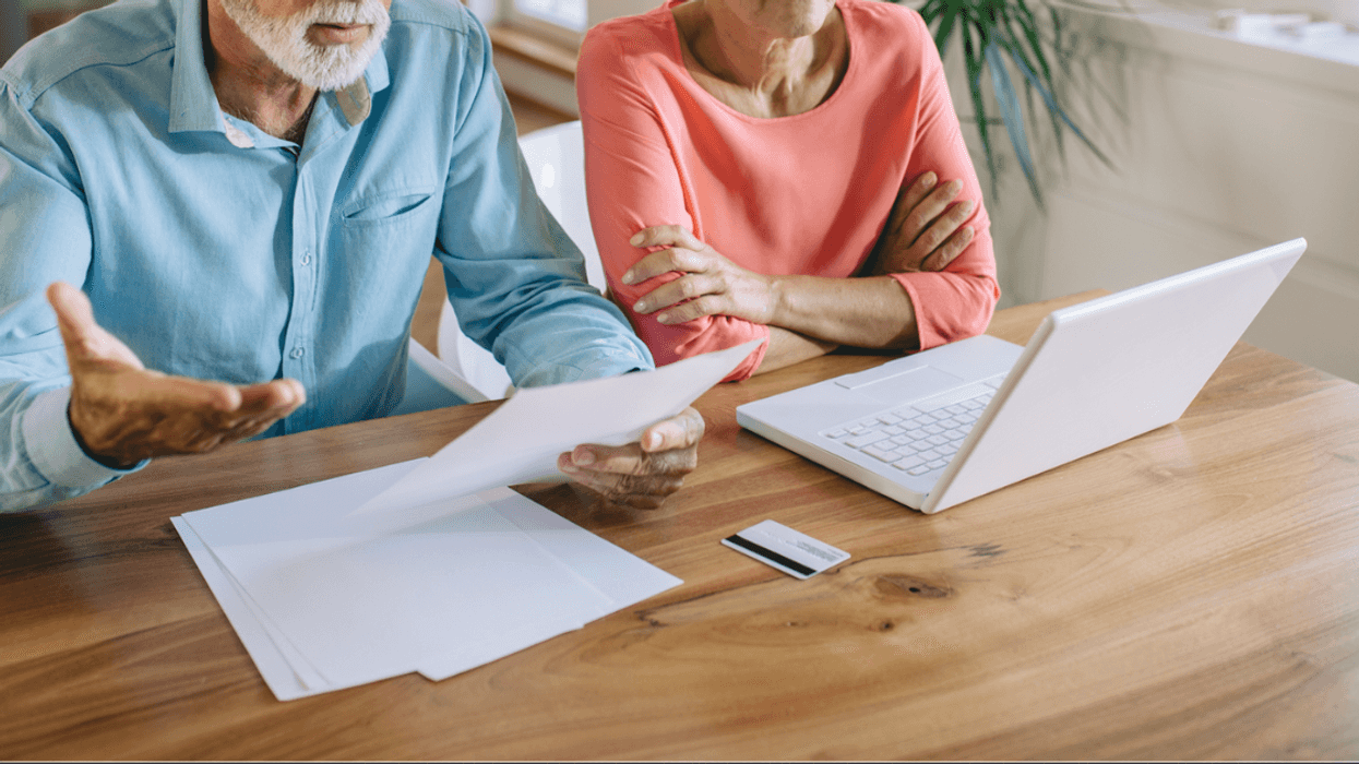 An older couple angrily looking at papers and a computer.
