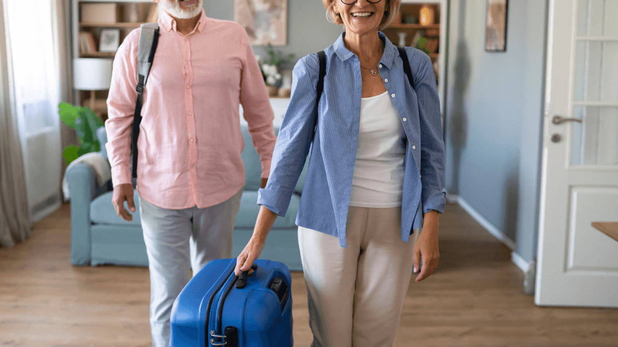 An older couple with luggage in a living room