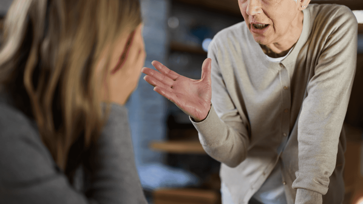An older woman gesturing to a younger woman with her head in her hands.